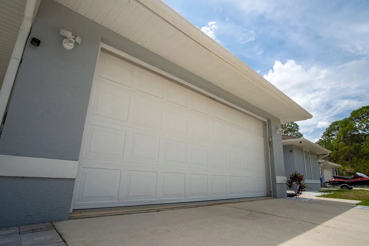 Attached garage with white raised-panel door