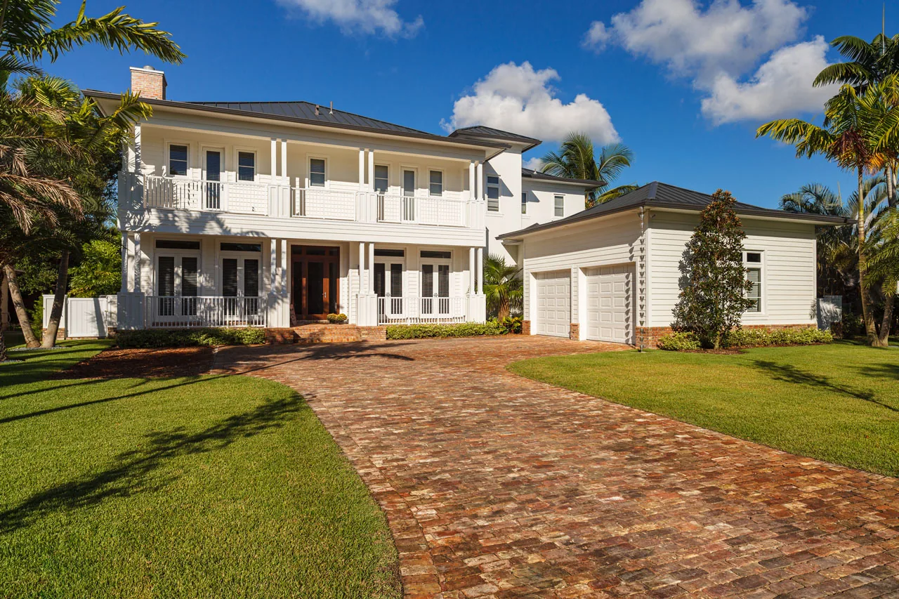 Two-story home with detached garage and brick driveway